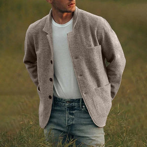 Men's light grey wool overshirt featuring a casual style with a button-up front, collared neckline, and long sleeves, worn by a bearded person standing in a grassy area.