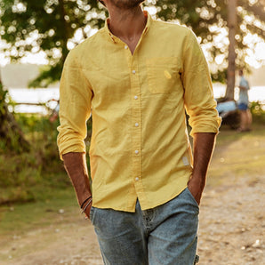 Men wearing a yellow linen shirt with a tailored fit, featuring a classic collar and long sleeves, standing outdoors near greenery.