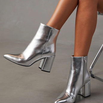 Silver high heel ankle boots showcased on a model's legs, highlighting the trendy metallic finish and sleek silhouette.