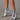 Metallic silver high heel ankle boots being worn, showcasing a trendy fashion statement with a focus on the sleek design and elevated heel.