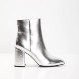 Metallic silver high heel ankle boots made of leather with a trendy fashion statement design, showcased in a still life photography setting.