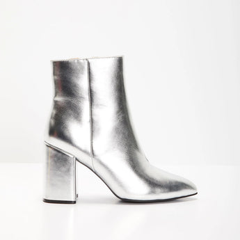 Metallic silver high heel ankle boots made of leather with a trendy fashion statement design, showcased in a still life photography setting.