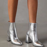 Metallic silver high heel ankle boots worn with a stylish dress, showcasing the trendy fashion statement and elegant design.