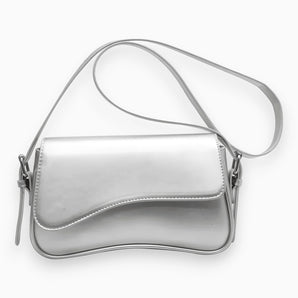 Metallic silver vegan leather crossbody bag with an adjustable strap, designed in a stylish hobo bag shape, suitable for fashion-forward events.
