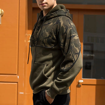 Men's military green tactical camo hoodie featuring a zip pocket, long sleeves, and a high collar, displayed against an urban backdrop.