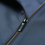 Minimalist dark blue men's bomber jacket laid flat on a surface, showcasing its lightweight and urban fashion design without any visible accessories or additional parts.