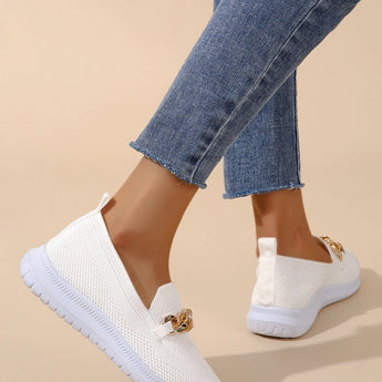 Minimalist white sneaker with seamless design and lightweight sole worn on a person dressed in denim jeans and an electric blue blazer.
