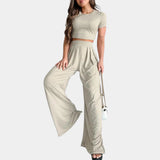 Mint green crop top paired with high-waisted, pleated khaki trousers, shown on a standing model. The outfit highlights the shoulders and waist, with the trousers featuring a loose fit around the thighs and legs.