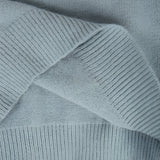 Mint green Fair Isle women's sweater with a cozy Scandinavian knit pattern, featuring intricate geometric designs in shades of grey and electric blue. The sweater is displayed against a wooden backdrop, highlighting the textile's texture and pattern.