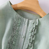 Mint green ruffled chiffon blouse with long sleeves and a collar, displayed on a wooden background.
