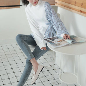Modern women's top featuring striped sleeves, styled casually with a focus on comfort.