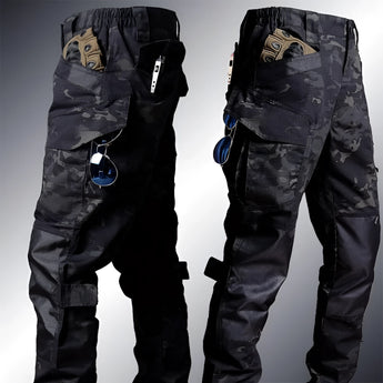 A person wearing a multi-camouflage tactical uniform, including a jacket and cargo pants, with gloves and headgear, standing outdoors.