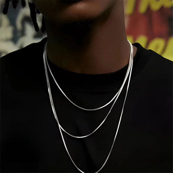 A woman wearing a multi-layer minimalist silver necklace, showcasing lightweight and versatile jewelry against a grey top.