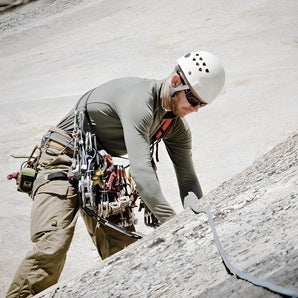Durable and breathable climbing pants with multiple pockets, designed for outdoor rock-climbing activities, worn by a climber on a rocky slope.