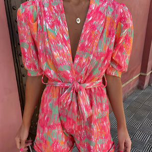 Multicolor abstract print belted summer romper in pink and green, featuring short sleeves, a collared neckline, and a cinched waist for a flattering fit.
