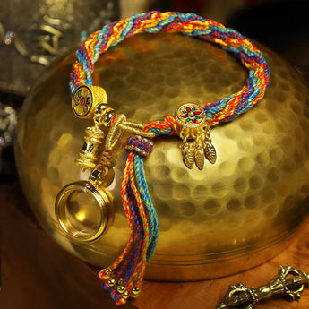 Colorful braided bracelet with ethnic charm, featuring adjustable tassels and intricate patterns, displayed close-up against a vibrant electric blue background.