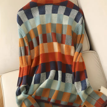 A woman wearing a multicolor plaid turtleneck sweater with long sleeves, featuring a cozy autumn knit design.