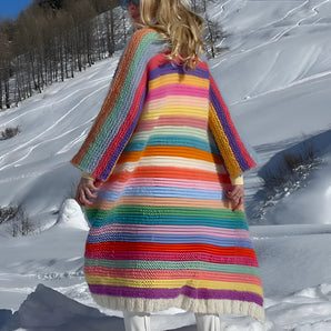 Women's wool poncho with multicolor stripes, featuring a cozy design suitable for winter fashion, displayed in a snowy outdoor setting.