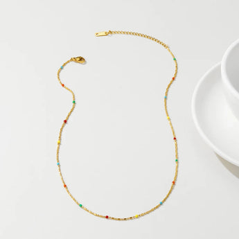 A multicolored gemstone necklace with gold beads displayed on a white background.