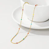 Multicolored gemstone necklace with gold accents displayed against a plain background.
