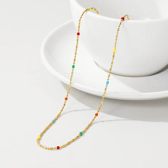 Multicolored gemstone necklace with gold accents displayed against a plain background.