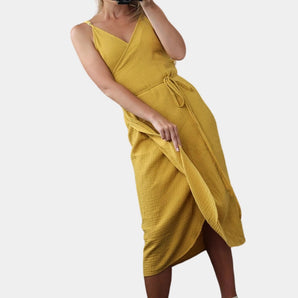 Mustard yellow ribbed wrap dress with asymmetric midi length and spaghetti straps, featuring a stylish design ideal for daytime wear.