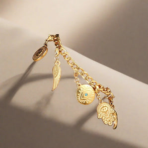 Mystical Gold Charm Bracelet with Owl, Eye, Feather Pendants in Boho Chic Style, featuring intricate gold details and natural elements in a close-up shot.