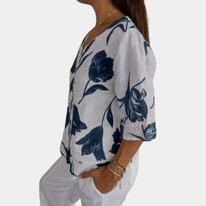 Navy blue floral linen blouse with a V-neck design, featuring short sleeves and a relaxed fit, suitable for casual summer wear.