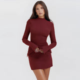 Navy blue high neck long sleeve mini dress with pockets worn by a fashion model, highlighting the dress's sophisticated collar and tailored fit around the waist and thighs. The model's arm and fingers are gently posed, showcasing the dress's elegant sleeves.