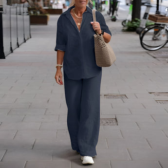 Navy blue linen summer suit for mature women, featuring a casual two-piece design with a dress shirt and tailored pants, modeled by a woman standing outdoors near a bicycle.