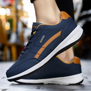 Navy blue men's dual-tone sneakers with a cushioned sole, designed for urban fashion. The athletic shoes feature a stylish blend of electric blue accents, perfect for walking and sportswear activities.