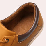Navy blue men's low-top leather sneakers displayed on a beige and brown natural material backdrop.