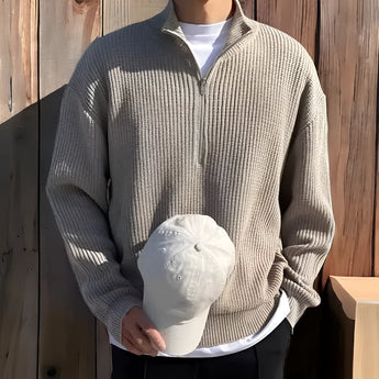 
Alt Text: A navy blue men's ribbed zip-up sweater displayed on a mannequin, showcasing its cozy fall fashion design. The sweater features a high collar, long sleeves, and a zip-up front, suitable for layering over a white dress shirt for a polished look.