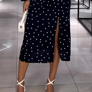 Navy blue evening dress with white polka dots, featuring long sleeves, a slit, and a knee-length design.