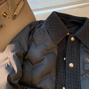 Navy blue quilted puffer jacket with a high-collar design, featuring long sleeves and a stylish, insulated winter coat construction.