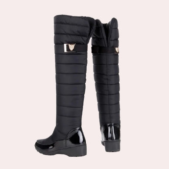 Navy blue quilted insulated women's winter boots with a glossy toe, featuring knee-high design and a synthetic rubber sole.