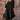 Woman wearing a black ruffle dress with a round neck, short sleeves, and fitted waist, standing upright.