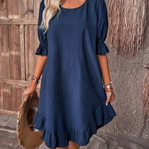 Woman wearing a navy blue ruffle dress with round neck and short sleeves, showcasing a chic and casual summer fashion style.