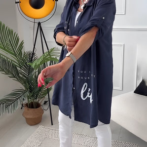 Navy blue shirt dress designed for casual summer wear, featuring long sleeves and a defined waist, modeled by a woman standing outdoors.