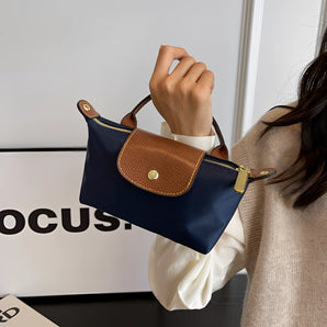 Navy blue and tan two-tone designer clutch for women, shown as a stylish shoulder bag with a sleek design, held in a hand.