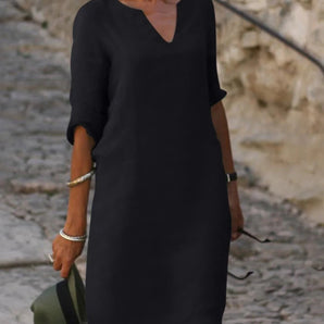 
Navy blue V-neck shift dress with three-quarter sleeves, designed in a lightweight fabric, shown on a model standing. The dress is a midi-length, featuring a relaxed fit with emphasis on the waist. The model is wearing a size 3XL in color Nero.