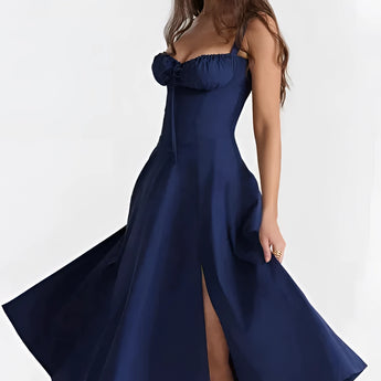 Navy ruched beach dress in marine blue, featuring an adjustable bust, modeled by a woman. The dress is a one-piece garment with a sleeveless design, highlighting the shoulders and arms.