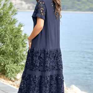 Navy tiered lace maxi dress worn by a woman with long hair, standing near a water backdrop, showcasing the elegant summer beachwear style with delicate lace detailing and a flowing silhouette.