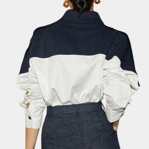 Navy and white contrast blouse with ruffled sleeves featuring a dress shirt style, showcasing the upper body, arm, and neck areas.