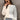 Neutral tone color-block sweater in gray, size XL, worn by a smiling woman pairing it with jeans and sunglasses.