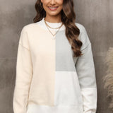 
A woman smiling while wearing a neutral tone color-block sweater featuring a fashionable design with a grey collar and sleeves, showcasing trendy fall knitwear for women.