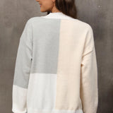 Neutral tone color-block sweater featuring long sleeves and a cozy knit design perfect for fall, with a stylish combination of grey and other muted tones that enhance its trendy and versatile look.