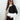
A woman smiling and wearing a trendy neutral tone color-block sweater in black, size XL. She is accessorized with sunglasses and holding a beverage. The sweater features a stylish neckline and long sleeves, ideal for fall fashion.