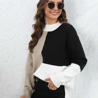 
A woman smiling and wearing a trendy neutral tone color-block sweater in black, size XL. She is accessorized with sunglasses and holding a beverage. The sweater features a stylish neckline and long sleeves, ideal for fall fashion.