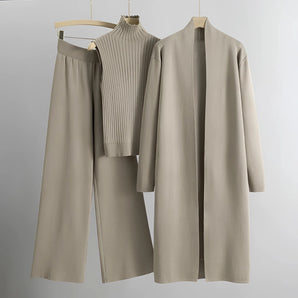 Women's fall outfit featuring a beige ribbed sweater with a high collar and long sleeves, paired with matching trousers, displayed on a clothes hanger.